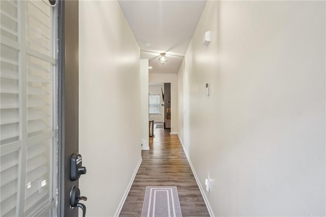 hallway featuring baseboards and dark wood finished floors