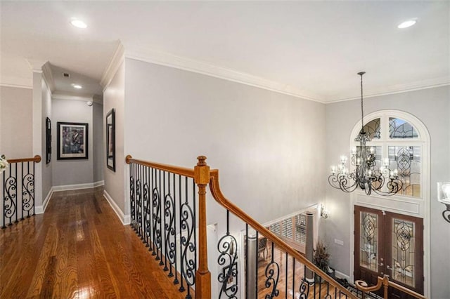 corridor with an inviting chandelier, baseboards, wood finished floors, and an upstairs landing