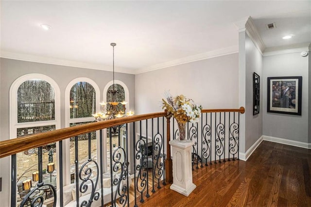 hall with a chandelier, visible vents, baseboards, ornamental molding, and dark wood finished floors