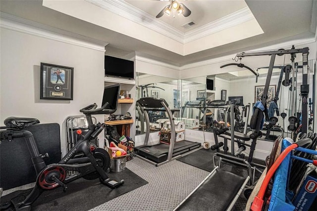 workout area with ceiling fan, visible vents, a raised ceiling, and ornamental molding