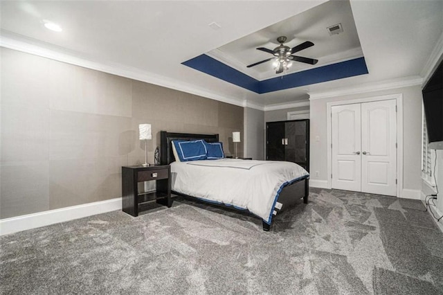 carpeted bedroom with baseboards, a tray ceiling, visible vents, and crown molding