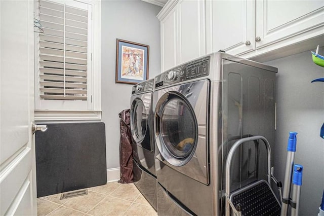 washroom featuring light tile patterned flooring, separate washer and dryer, visible vents, baseboards, and cabinet space