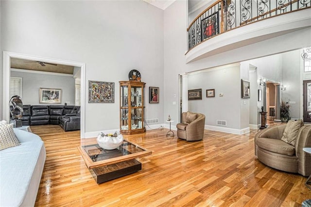 living area featuring baseboards, visible vents, a high ceiling, and wood finished floors