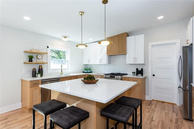 kitchen featuring backsplash, a center island, a breakfast bar, appliances with stainless steel finishes, and a sink