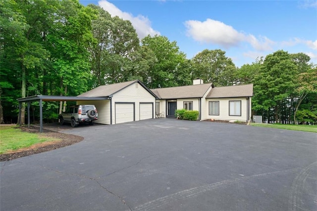 6125 Jim Crow Rd, Flowery Branch, GA 30542 - ranch-style house featuring a chimney, view of wooded area, an attached garage, and driveway