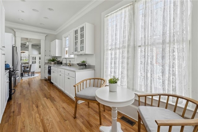 kitchen featuring sink, crown molding, light hardwood / wood-style flooring, white cabinets, and black appliances