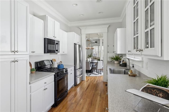 kitchen with white cabinets, ornamental molding, sink, and black appliances