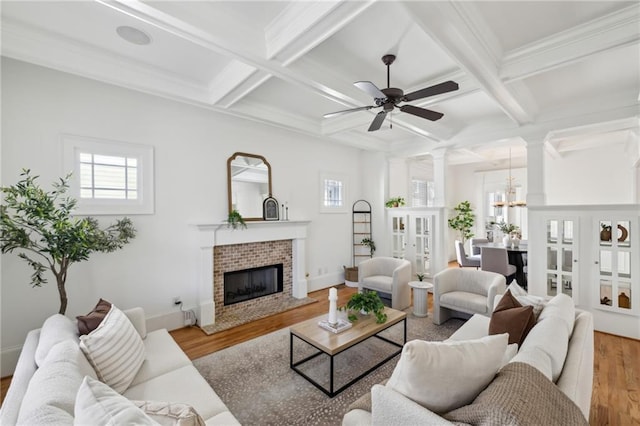 living room featuring ornate columns, a brick fireplace, a healthy amount of sunlight, and light hardwood / wood-style flooring