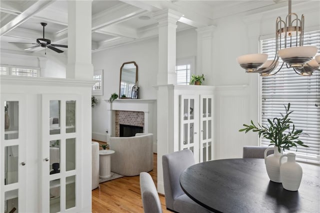 dining space with crown molding, ceiling fan, ornate columns, coffered ceiling, and light wood-type flooring