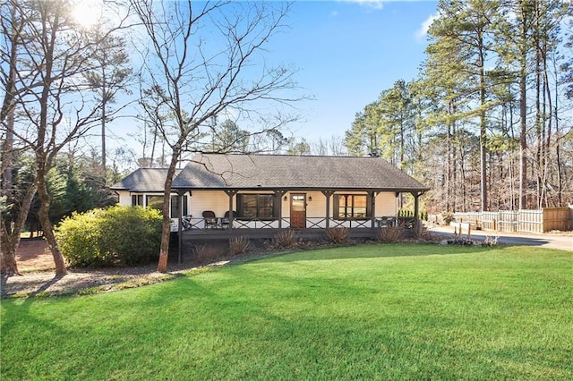 rear view of house with a porch, a yard, and fence