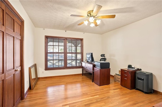 office featuring light wood-style flooring, a textured ceiling, baseboards, and a ceiling fan