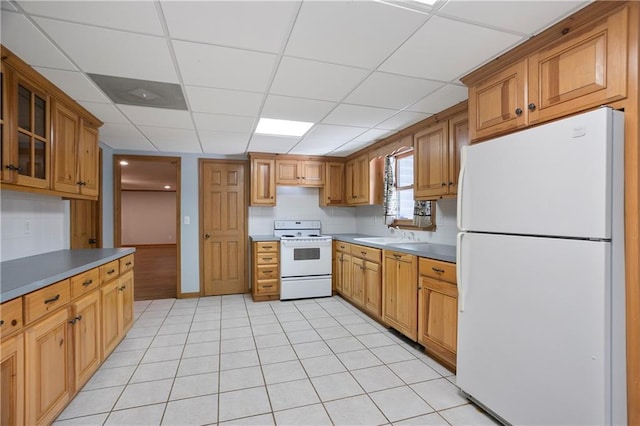 kitchen featuring glass insert cabinets, white appliances, brown cabinets, and light tile patterned floors