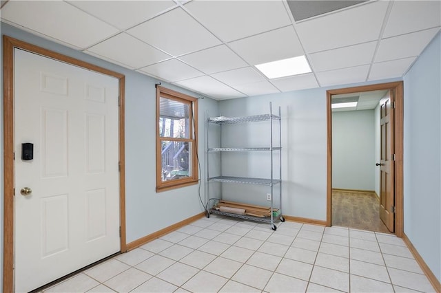 spare room featuring a paneled ceiling, baseboards, and light tile patterned flooring