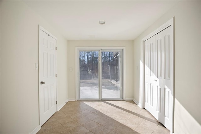 doorway featuring baseboards and light tile patterned flooring