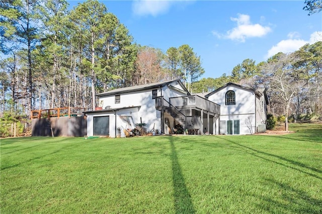 rear view of house featuring stairs, a yard, a deck, and a garage