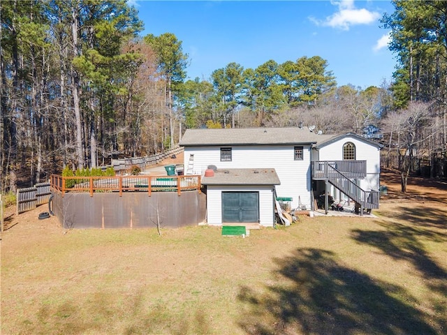 rear view of property with fence, stairs, a lawn, a wooden deck, and a swimming pool