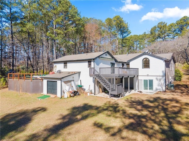 back of property featuring a garage, a lawn, stairs, a wooden deck, and a pool