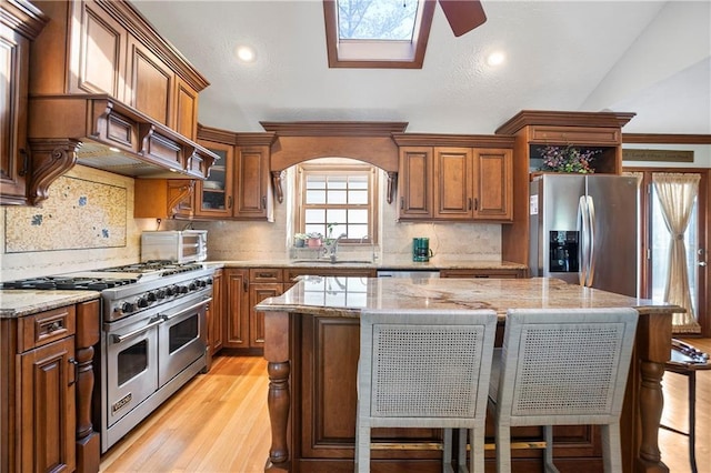 kitchen with stainless steel appliances, a center island, brown cabinetry, and a breakfast bar