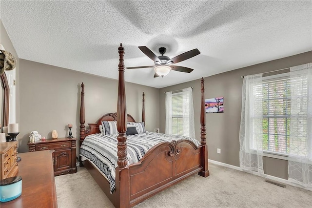 bedroom with ceiling fan, light colored carpet, a textured ceiling, baseboards, and visible vents