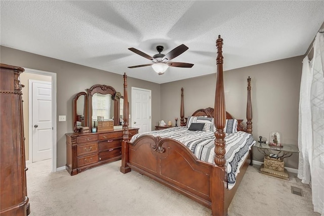 bedroom featuring baseboards, a textured ceiling, light colored carpet, and ceiling fan