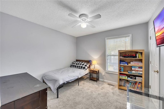 carpeted bedroom with visible vents, a textured ceiling, ceiling fan, and baseboards