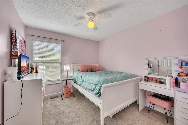 bedroom featuring a ceiling fan, a textured ceiling, light carpet, and baseboards