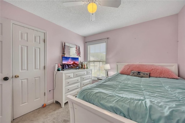 bedroom with a ceiling fan, a textured ceiling, and light carpet