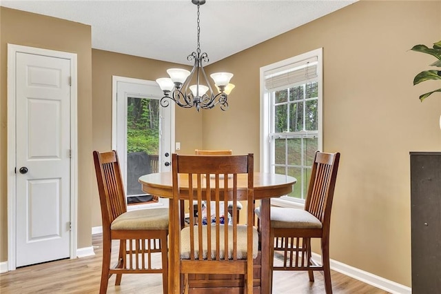 dining room with plenty of natural light, baseboards, a notable chandelier, and light wood-type flooring