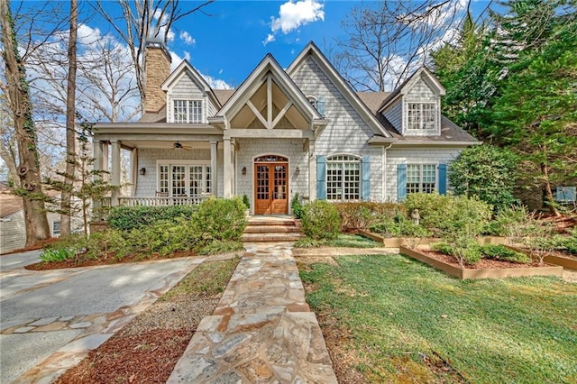 view of front of house featuring french doors, a chimney, and a front lawn