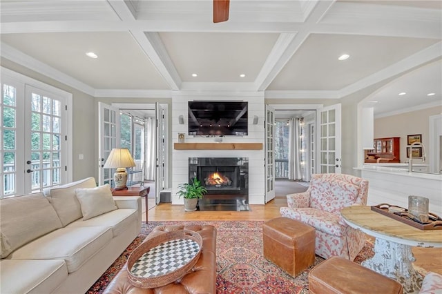 living room featuring beamed ceiling, coffered ceiling, wood finished floors, french doors, and crown molding