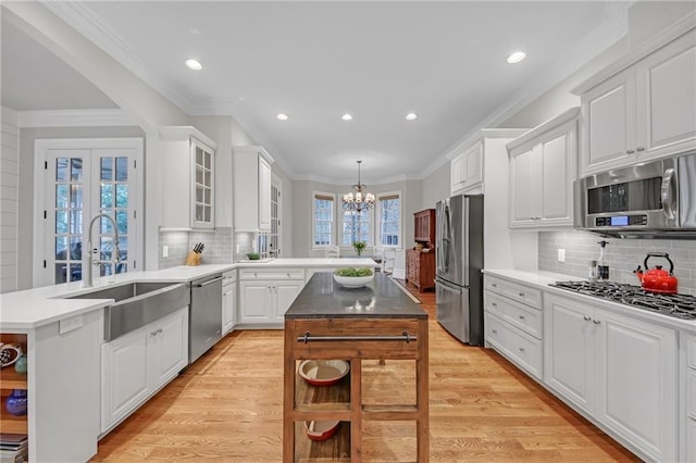 kitchen featuring a sink, a center island, stainless steel appliances, a peninsula, and a chandelier