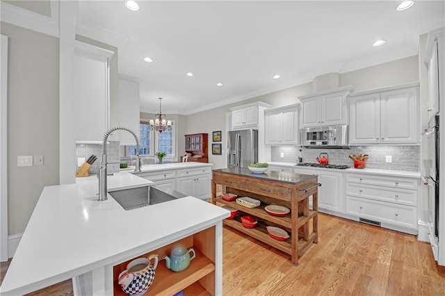 kitchen featuring open shelves, a peninsula, a sink, stainless steel appliances, and white cabinets