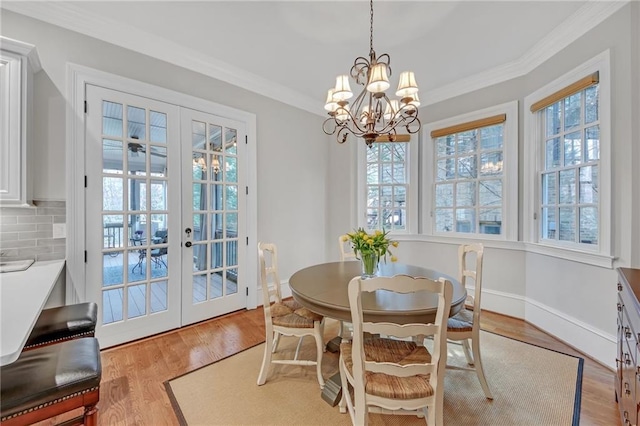 dining area featuring french doors, plenty of natural light, crown molding, and light wood finished floors