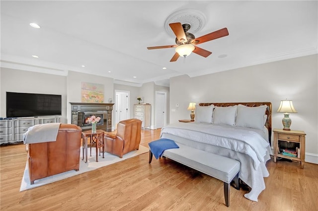 bedroom featuring light wood finished floors, recessed lighting, baseboards, and a lit fireplace