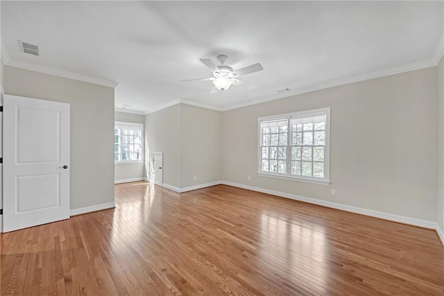 spare room featuring light wood finished floors, visible vents, ceiling fan, and ornamental molding