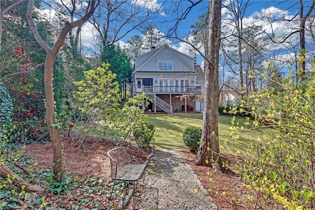 back of property featuring stairway, a lawn, and a deck