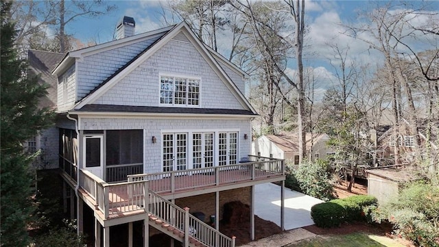 back of house featuring a deck, stairs, a sunroom, and a chimney