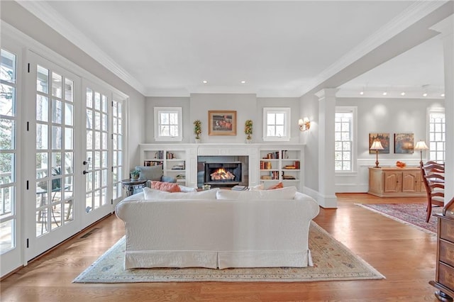 living area with a glass covered fireplace, visible vents, wood finished floors, and crown molding