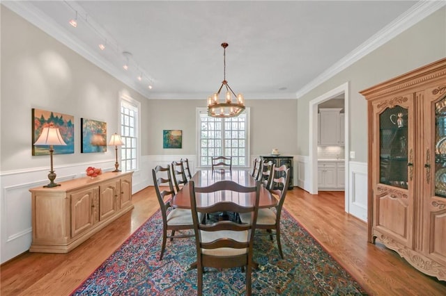 dining space featuring a chandelier, wainscoting, light wood-style floors, and ornamental molding