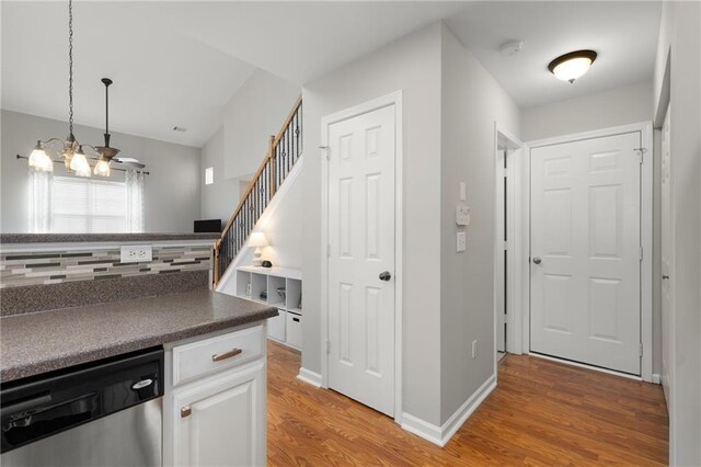 kitchen featuring decorative light fixtures, white cabinets, decorative backsplash, hardwood / wood-style flooring, and stainless steel dishwasher