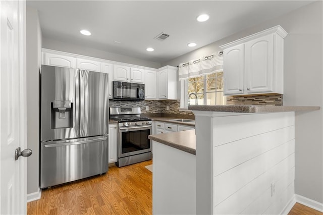 kitchen featuring sink, white cabinetry, light hardwood / wood-style flooring, kitchen peninsula, and stainless steel appliances