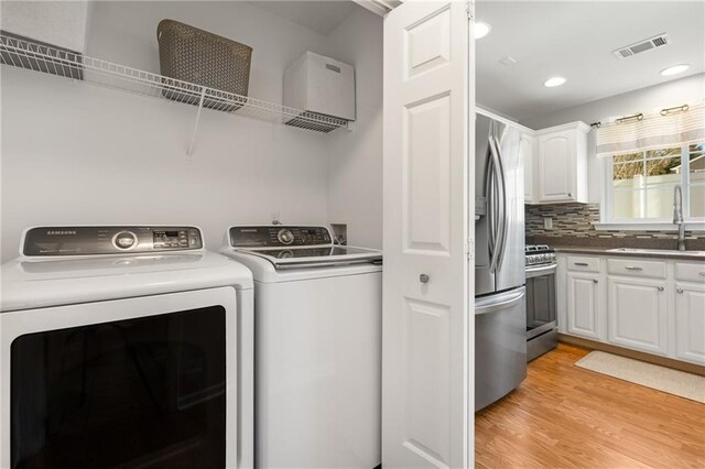 laundry room with sink, independent washer and dryer, and light hardwood / wood-style floors