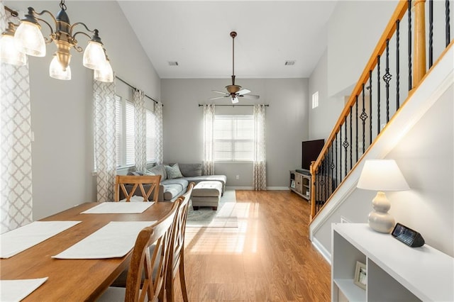 dining space featuring ceiling fan with notable chandelier and light hardwood / wood-style flooring