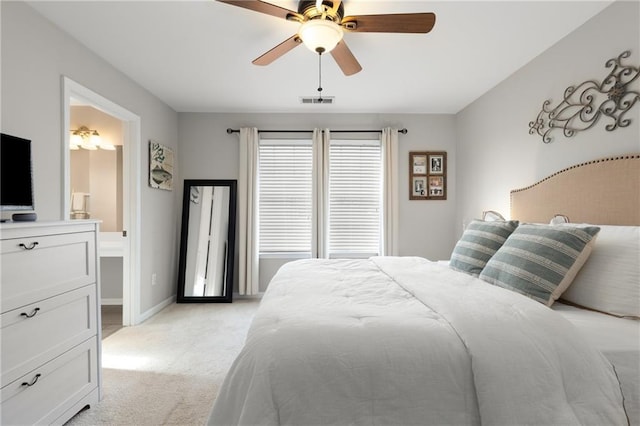 bedroom featuring light carpet, ceiling fan, and ensuite bathroom