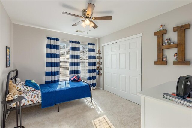 carpeted bedroom with ceiling fan and a closet