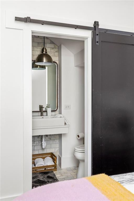 bedroom featuring a barn door, connected bathroom, and baseboards