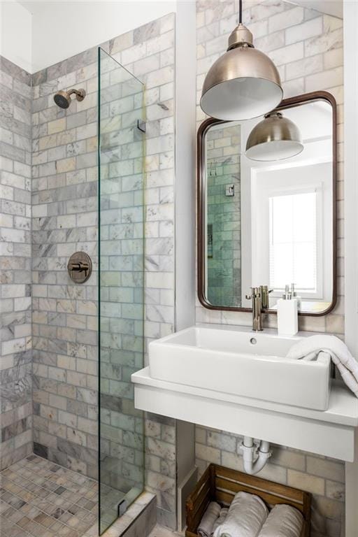 full bathroom featuring tiled shower and a sink