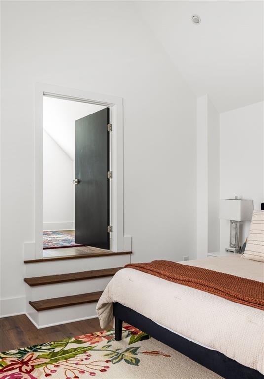 bedroom with vaulted ceiling and wood finished floors