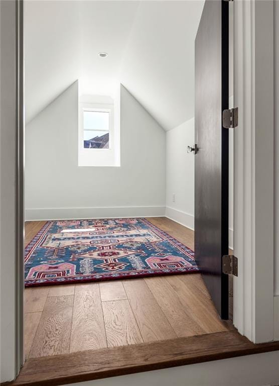 additional living space featuring baseboards, vaulted ceiling, and wood finished floors