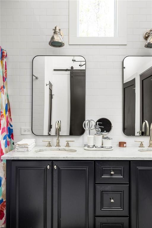 bathroom with double vanity, backsplash, and a sink